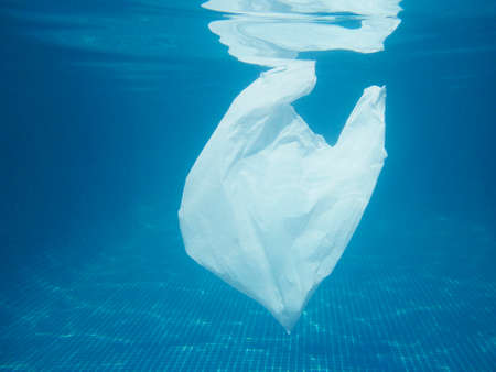 Plastic bag floating into the water. Polluted enviromental. Recycle garbage