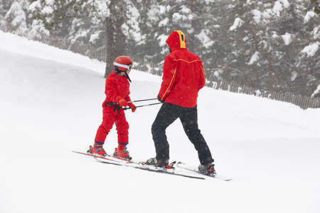 Child learning how to ski with an instructor. Winter sportの写真素材