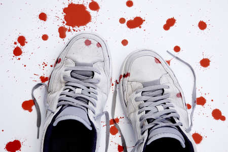 Used sneakers with blood isolated on white. Violence against childrenの写真素材