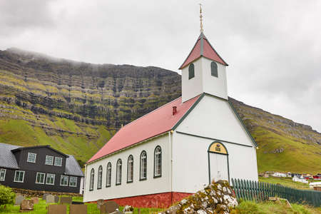 Traditional Faroe village of  Kunoy with picturesque church and mountainの写真素材