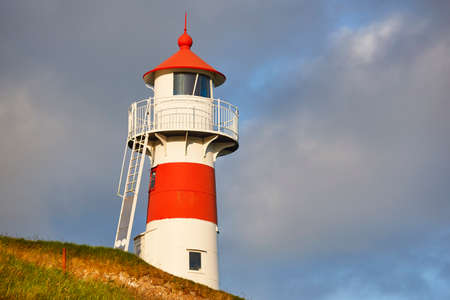 Red and white classic lighthouse in Faroe islands, Torshavn harborの写真素材