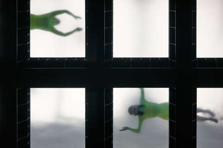 Glass bottom swimming pool with swimmers viewed from above. Underwater