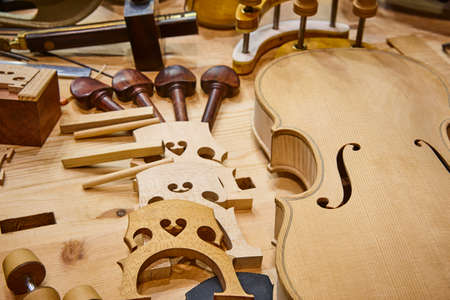 Luthier workshop with violin wooden parts and tools. Traditional craftmanship.