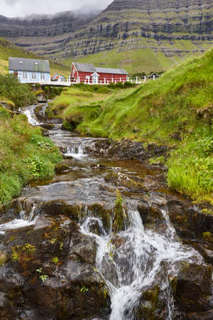 Traditional Faroe village of  Kunoy with picturesque stream and mountainの写真素材
