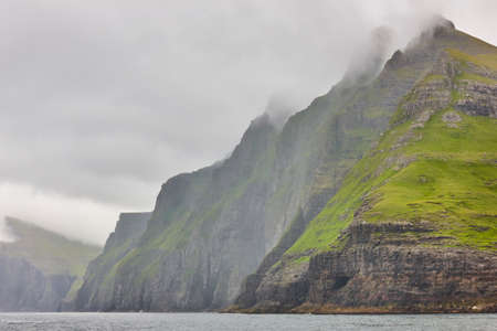 Picturesque green cliffs and atlantic ocean in Faroe islands.