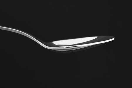 Stainless steel spoon over a black background. Restaurant food and drinkの写真素材