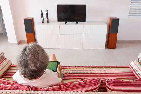 Mature woman reading a tablet in the living room. Lifestyle