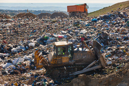 Heavy machinery shredding garbage in an open air landfill. Waste
