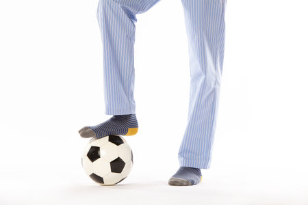 Young man in pajama playing football. Legs detail. Night wearの写真素材