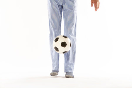 Young man in pajama playing football. Legs detail. Night wearの写真素材
