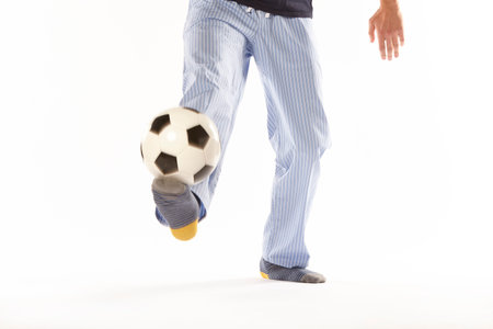 Young man in pajama playing football. Legs detail. Night wearの写真素材