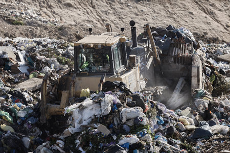Heavy machinery shredding garbage in an open air landfill. Waste