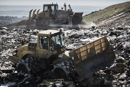 Heavy machinery shredding garbage in an open air landfill. Waste