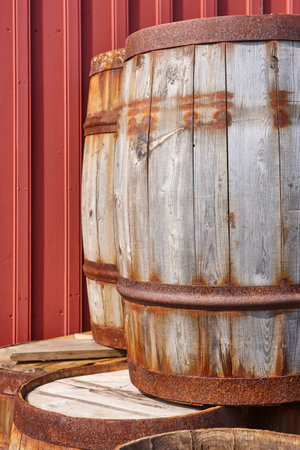 Rusty wooden barrels and red wall background.