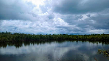 A small lake covered by mangroves below a cloudy sky at Mantehage Island, North Sulawesi, Indonesiaの写真素材
