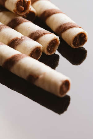 wafer rolls with nut filling on a mirrored background.