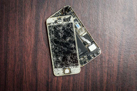 A broken and damage hand phone isolated over wooden backgroundのeditorial素材