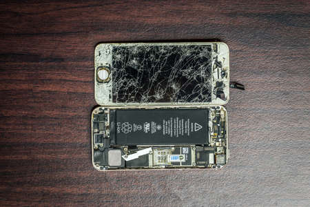 A broken and damage hand phone isolated over wooden backgroundのeditorial素材