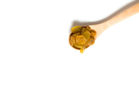 A dried raisin in a wooden spoon isolated over white background