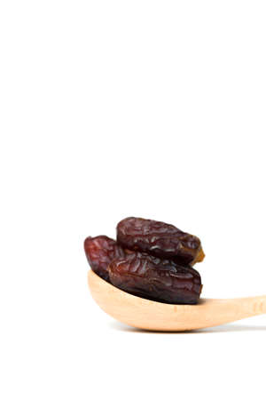 A dried dates in a wooden spoon isolated over white backgroundの写真素材