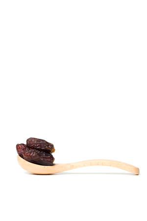 A dried dates in a wooden spoon isolated over white backgroundの写真素材