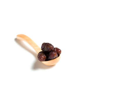 A dried dates in a wooden spoon isolated over white background