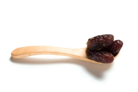 A dried dates in a wooden spoon isolated over white backgroundの写真素材