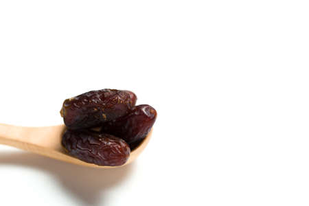 A dried dates in a wooden spoon isolated over white backgroundの写真素材