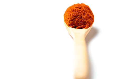 A chili powder in a wooden spoon isolated over white backgroundの写真素材