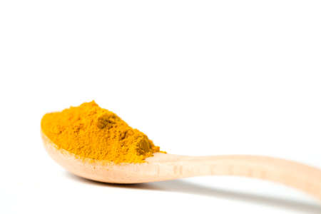 A turmeric powder in a wooden spoon isolated white backgroundの写真素材