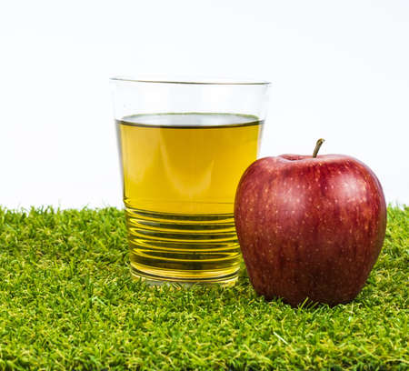 Close-up an apple beside a glass of apple juice on the artificial grass の写真素材