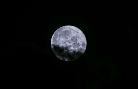 The full moon is covered with clouds, the moon is among the cloudsの写真素材