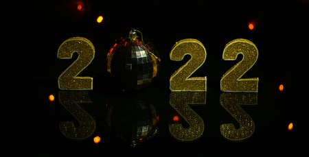 New 2022, gold figures and lights are reflected in the mirror on a black background