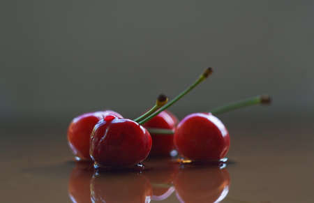 The red cherry stands on a glass sheet and the mirror reflects the red cherry