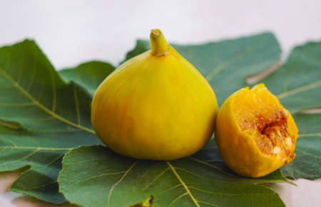 There is a yellow fig on the table with its leavesの写真素材