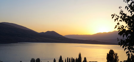 At sunset, the lake and houses can be seen at the foot of the mountainの写真素材