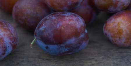 Ripe large plums are scattered on the table.の写真素材