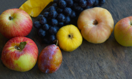 On the board are black grapes, yellow leaves, and various fruits