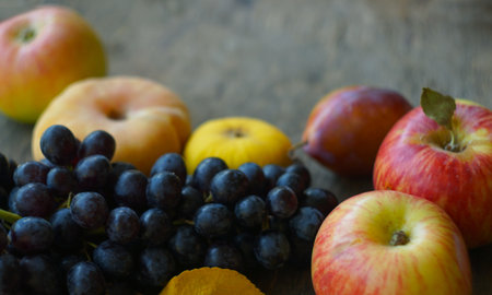 On the board are black grapes, yellow leaves, and various fruitsの写真素材