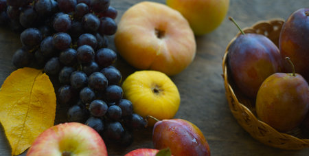 On the board are black grapes, yellow leaves, and various fruits.