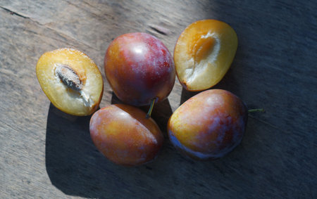 In nature, a cut and whole plum stands on a boardの写真素材
