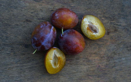 In nature, a cut and whole plum stands on a boardの写真素材