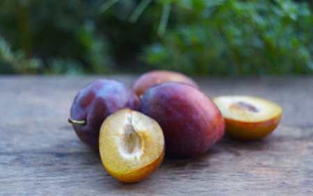 In nature, a cut and whole plum stands on a boardの写真素材