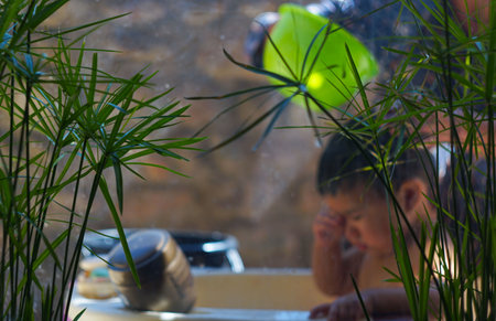Behind the mirror, a child is taking a bath.の写真素材