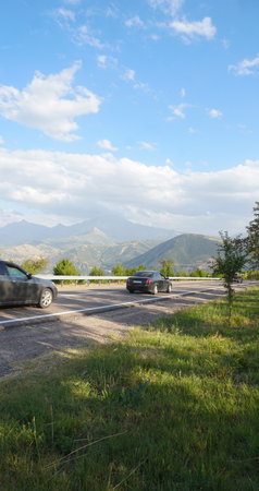 Cars are driving on the road leading towards the mountain.