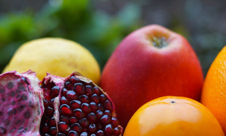 There is a piece of pomegranate and other fruits on the table, The cut pomegranate stands in the...