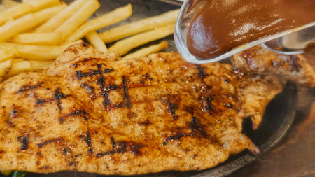 Juicy grilled chicken steak served with crispy french fries and colorful fresh vegetables, perfect for restaurant menu, food advertising, and commercial culinary contentの写真素材