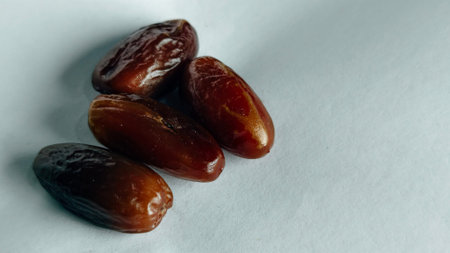 Fresh dates fruit close up isolated on white background for healthy natural snack concept, showcasing glossy texture and rich brown color perfect for food advertising, nutrition coの写真素材