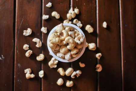 Popcorn in a bowl and some popcorn fall on a wooden table. selective focus