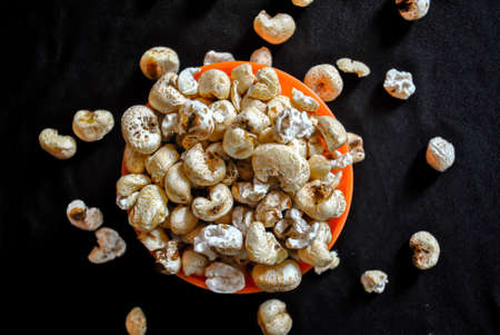 Pop corn in an orange bowl isolated on black background. Dark background. Selective focus